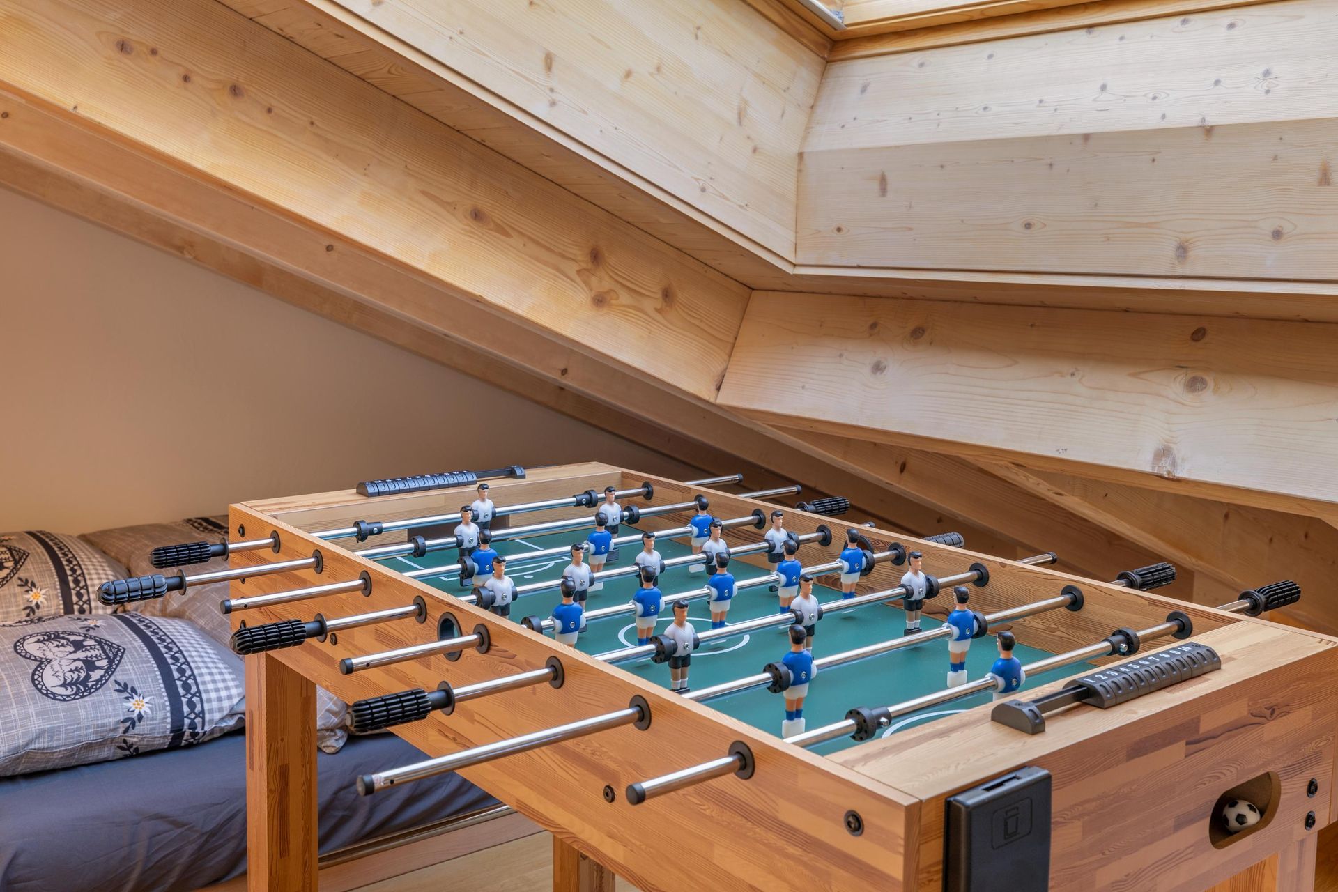Un baby-foot se trouve dans le grenier à côté d'un lit.