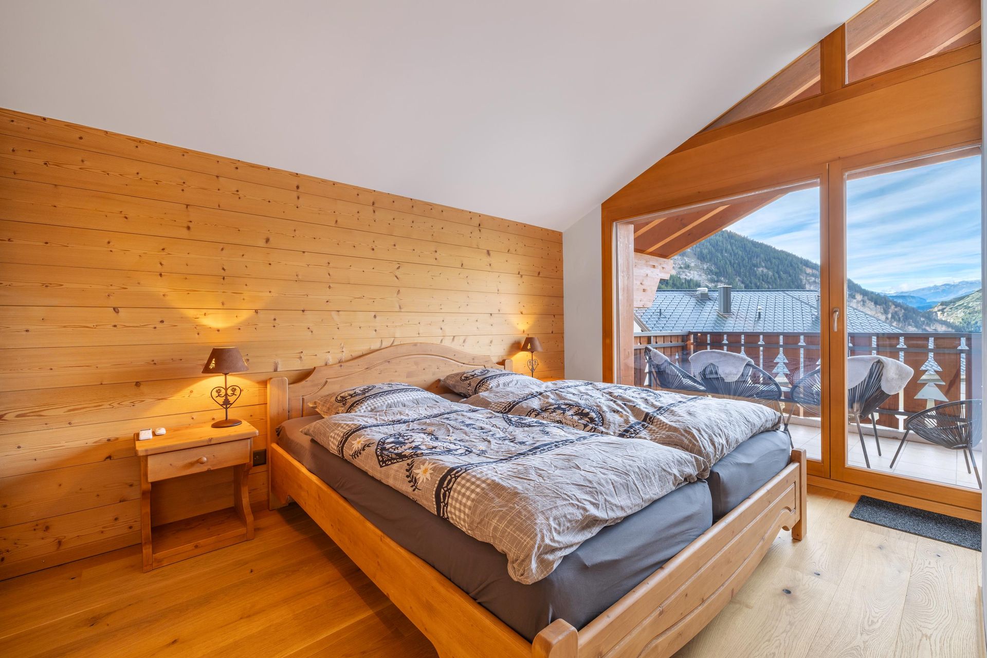 Une chambre avec un grand lit et un balcon avec vue sur les montagnes.