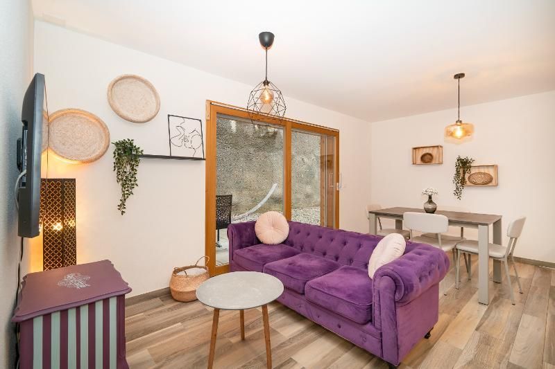 Un salon avec un canapé violet, une table et des chaises.