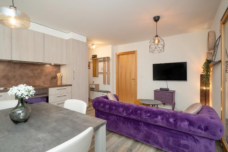 Un salon avec un canapé violet et une télévision à écran plat.