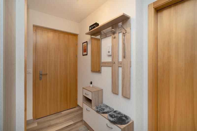 Un couloir avec des portes en bois et un porte-manteau.