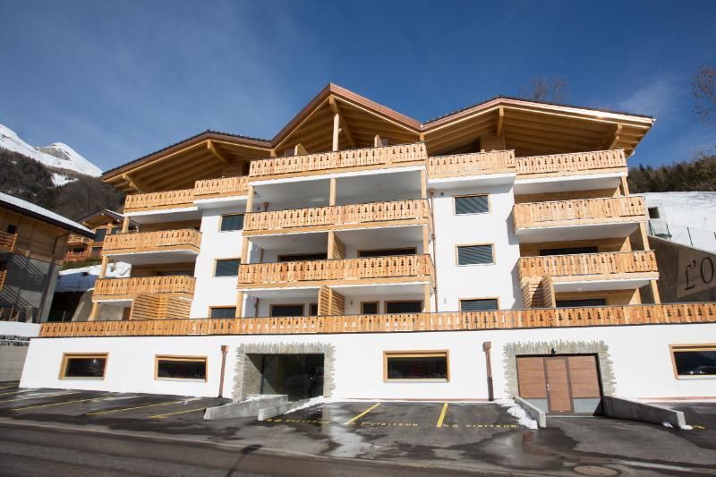 Un grand bâtiment blanc avec des balcons en bois est assis au sommet d'une colline couverte de neige.