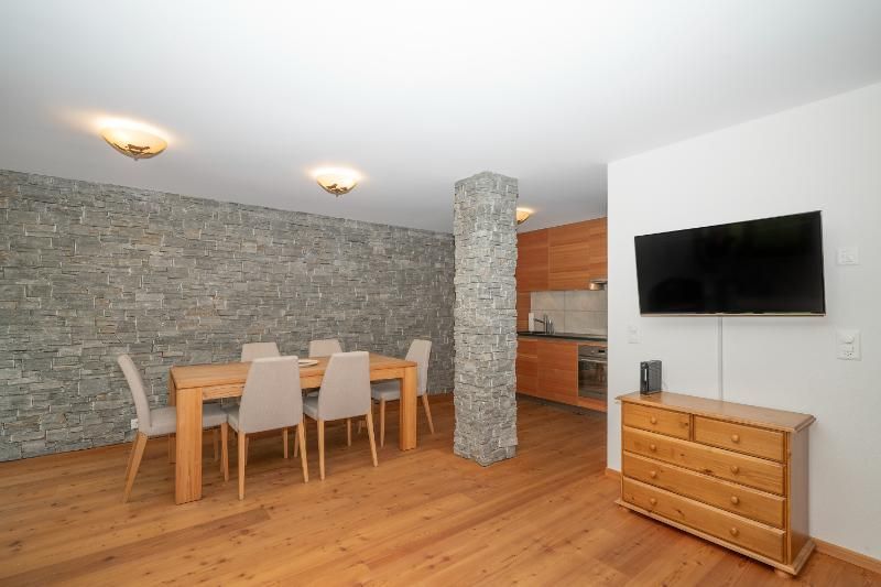 Un séjour avec une table à manger et des chaises et une télévision à écran plat.