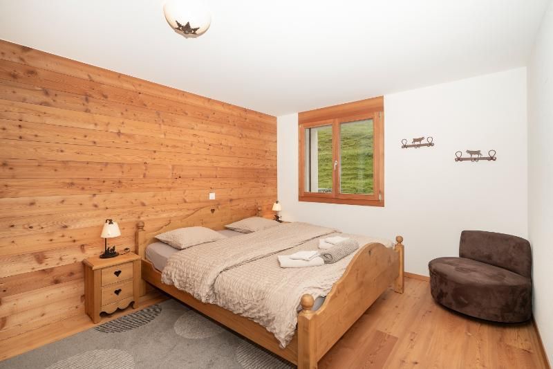 Une chambre avec un lit, une table de nuit, une chaise et une fenêtre.