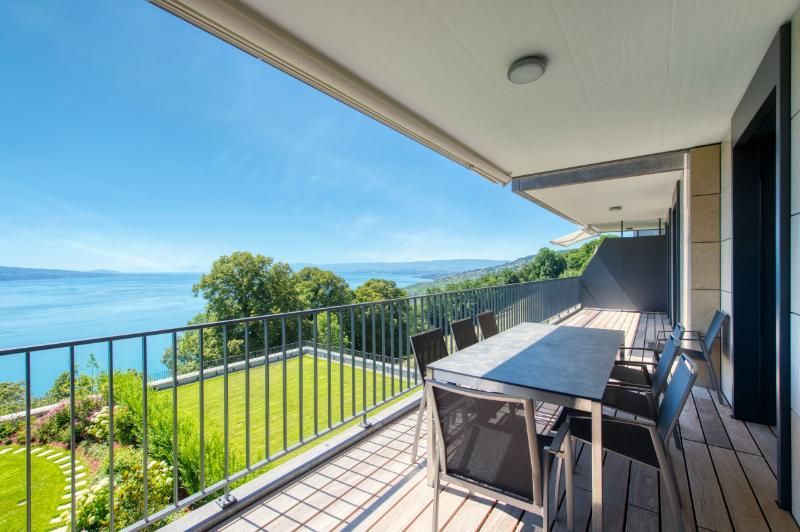 Un balcon avec une table et des chaises donnant sur un lac.