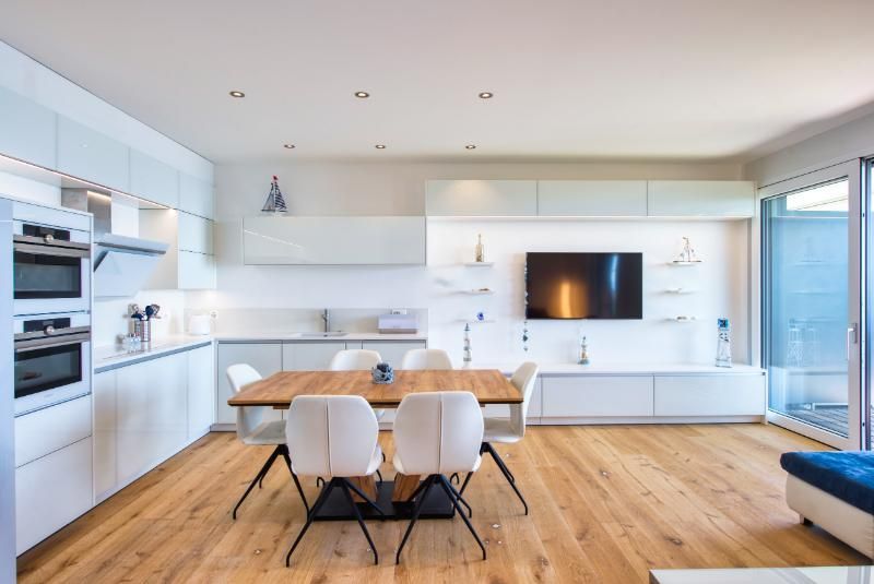Une cuisine avec une table à manger et des chaises et une télévision au mur.