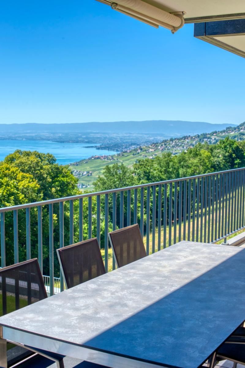 Une table et des chaises sur un balcon donnant sur un lac