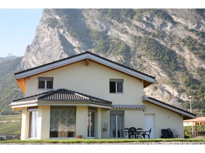 Une maison blanche avec une montagne en arrière-plan