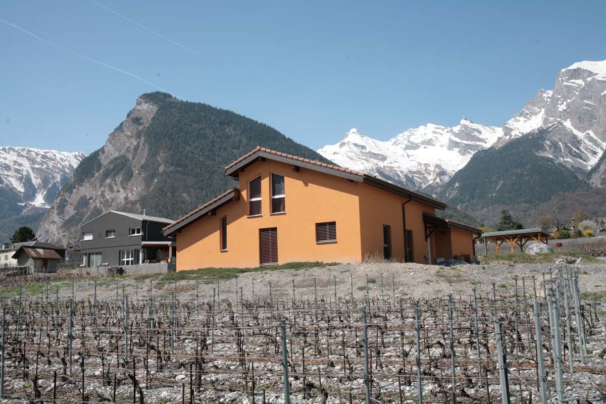 Une maison dans un champ avec des montagnes en arrière-plan