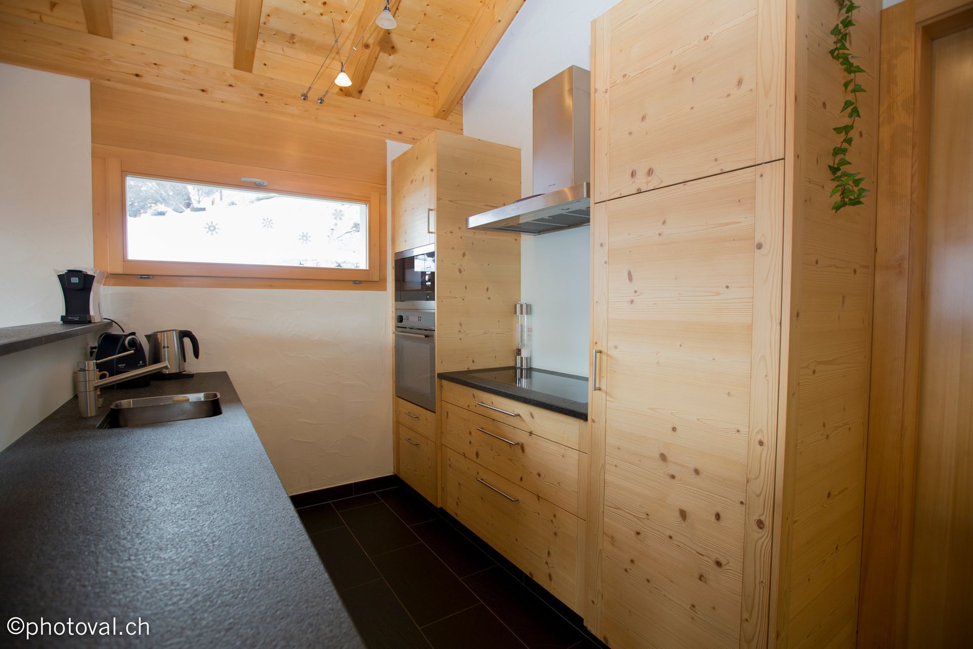 Une cuisine avec des armoires en bois et un comptoir noir.