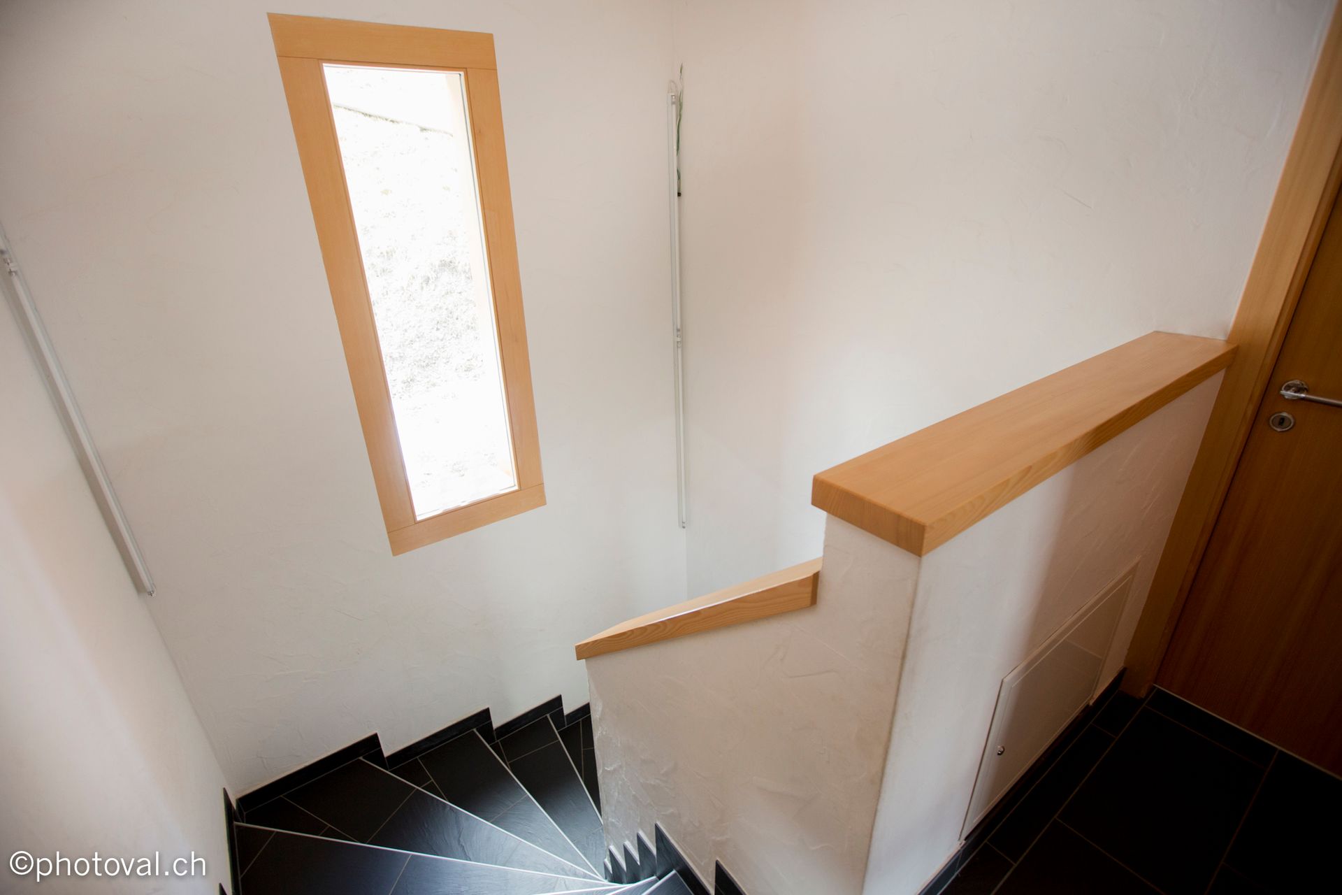 Un escalier avec une fenêtre et une rampe en bois