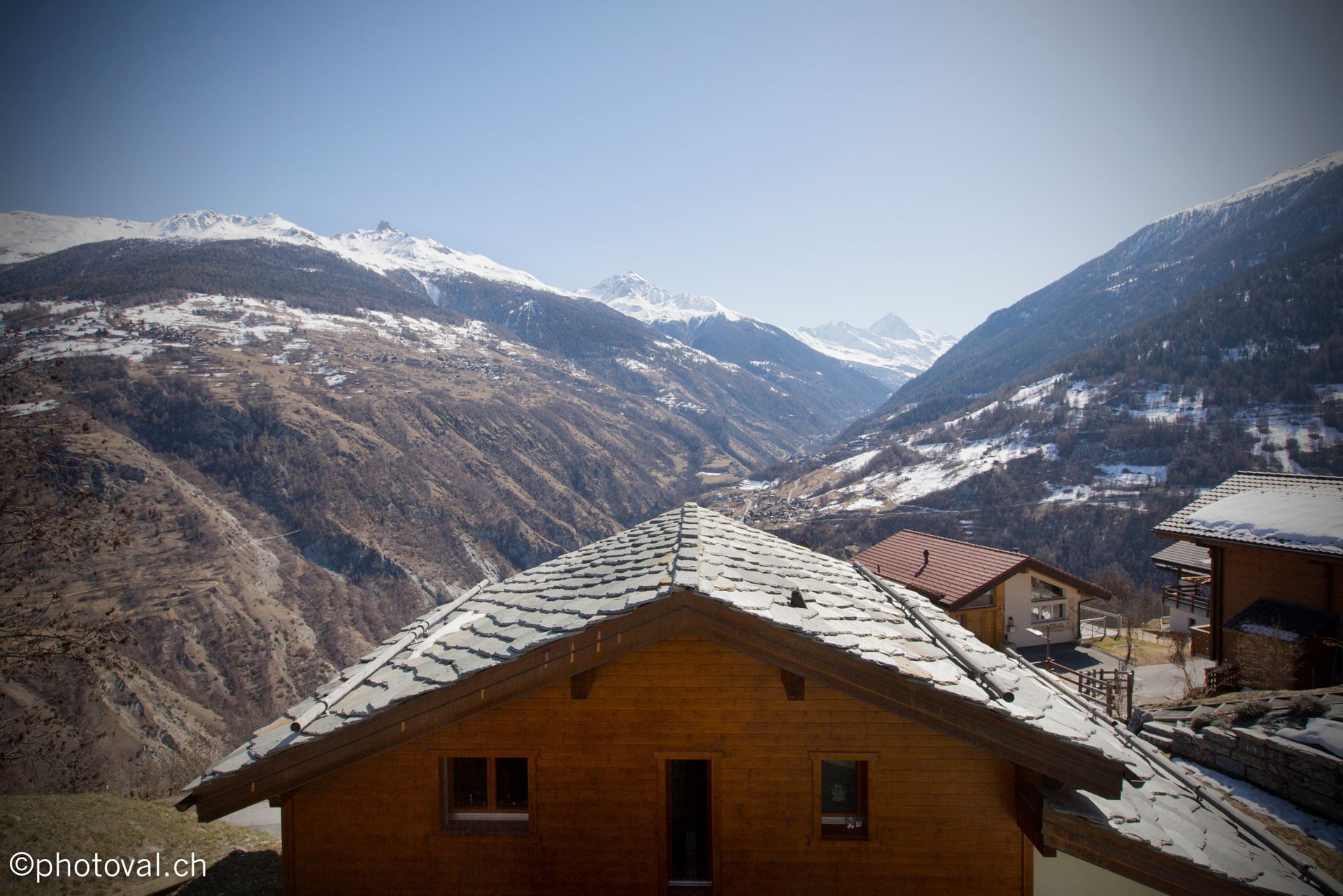 Une maison au milieu d'une vallée enneigée avec des montagnes en arrière-plan