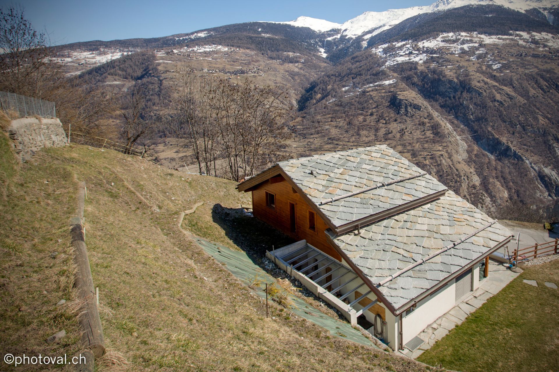 Une vue aérienne d'une maison sur une colline avec des montagnes en arrière-plan