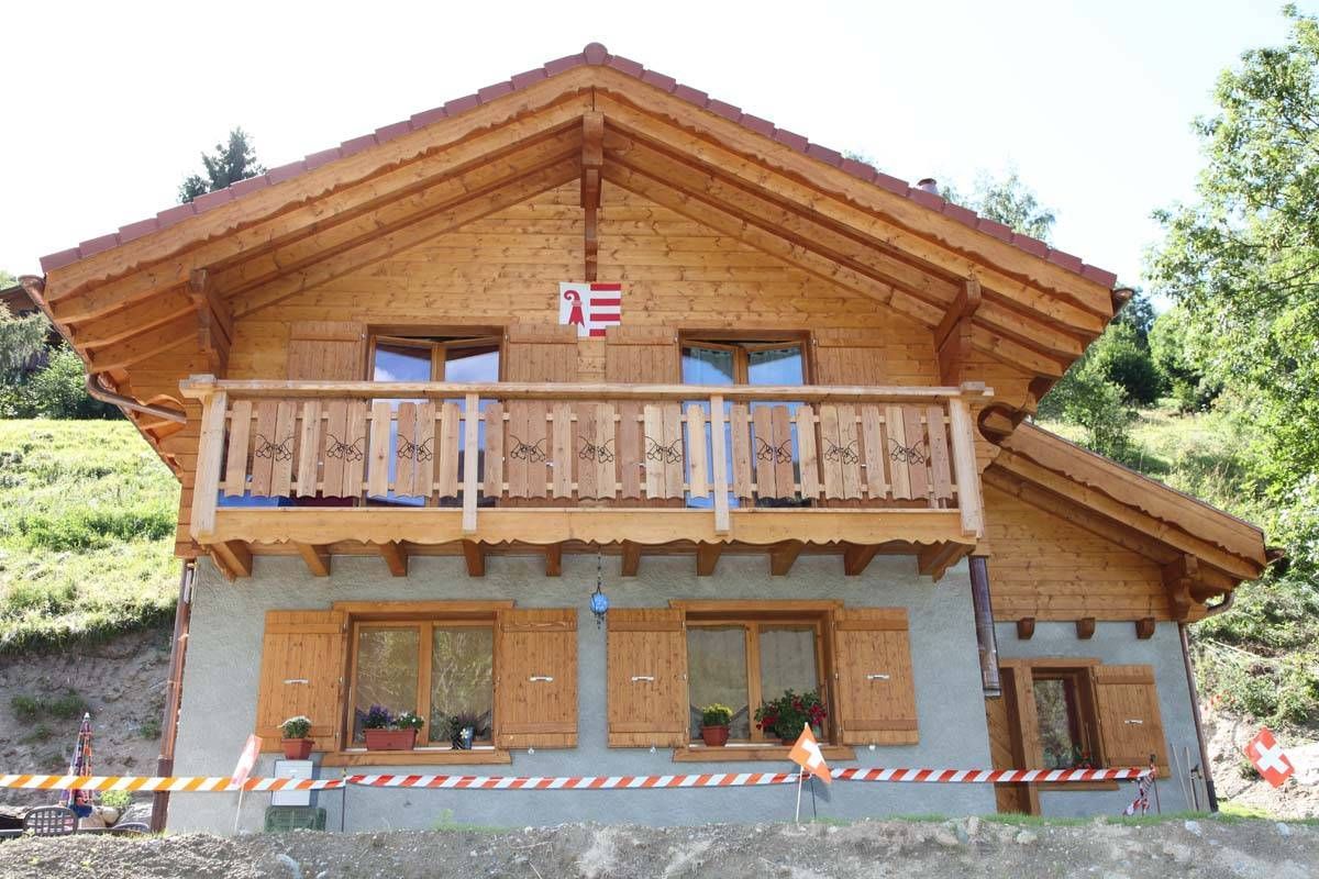 Une maison en bois avec un balcon et un drapeau sur le toit.