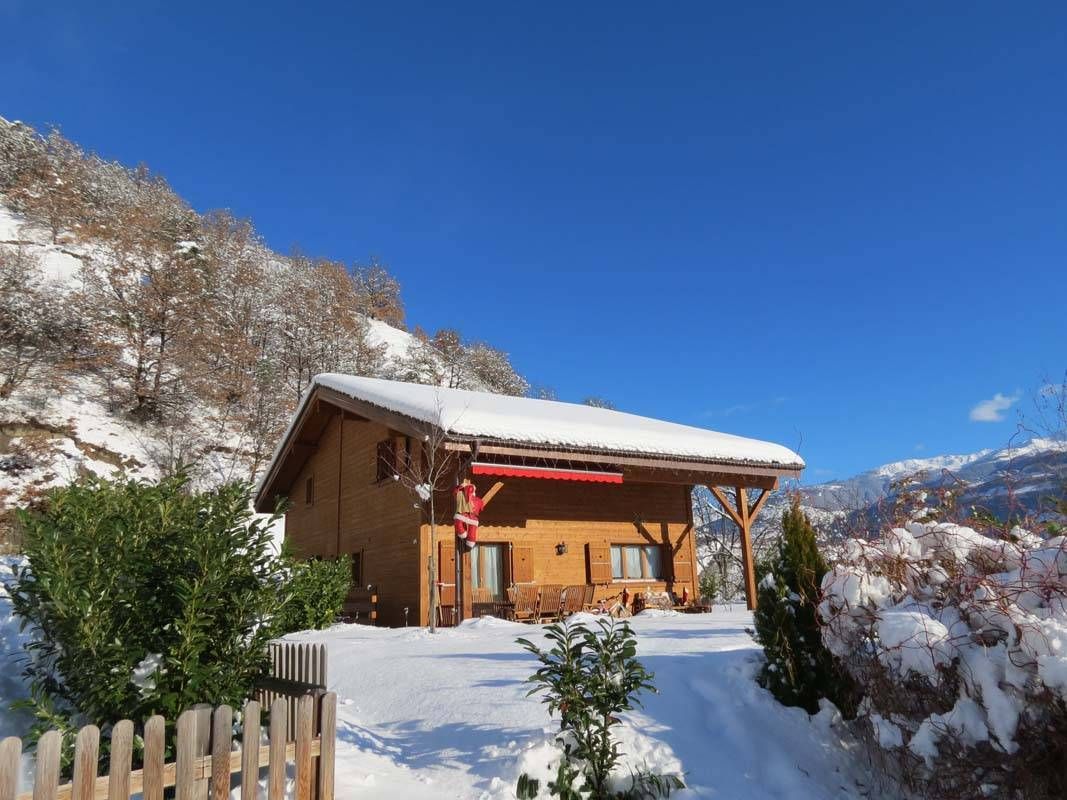 Une maison en bois est recouverte de neige dans les montagnes.