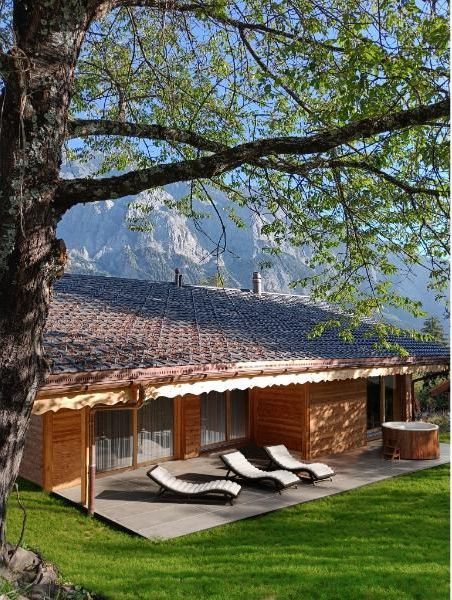 Une maison avec un patio et des chaises devant.