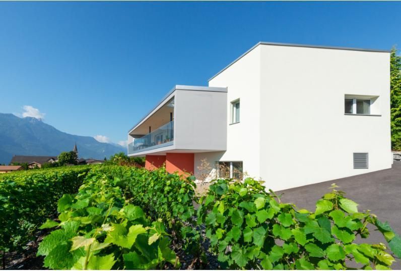 Une maison blanche avec un balcon et un vignoble devant