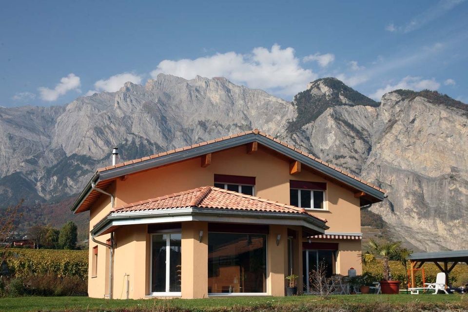 Une maison avec des montagnes en arrière-plan et un belvédère devant