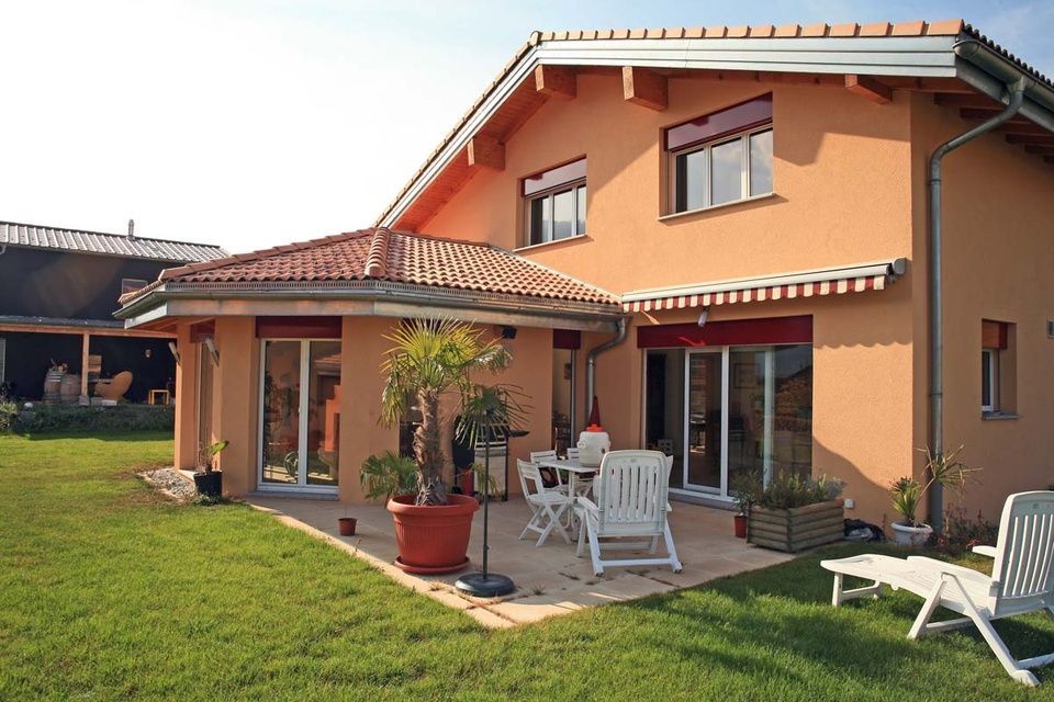 Une maison avec un patio et des chaises devant