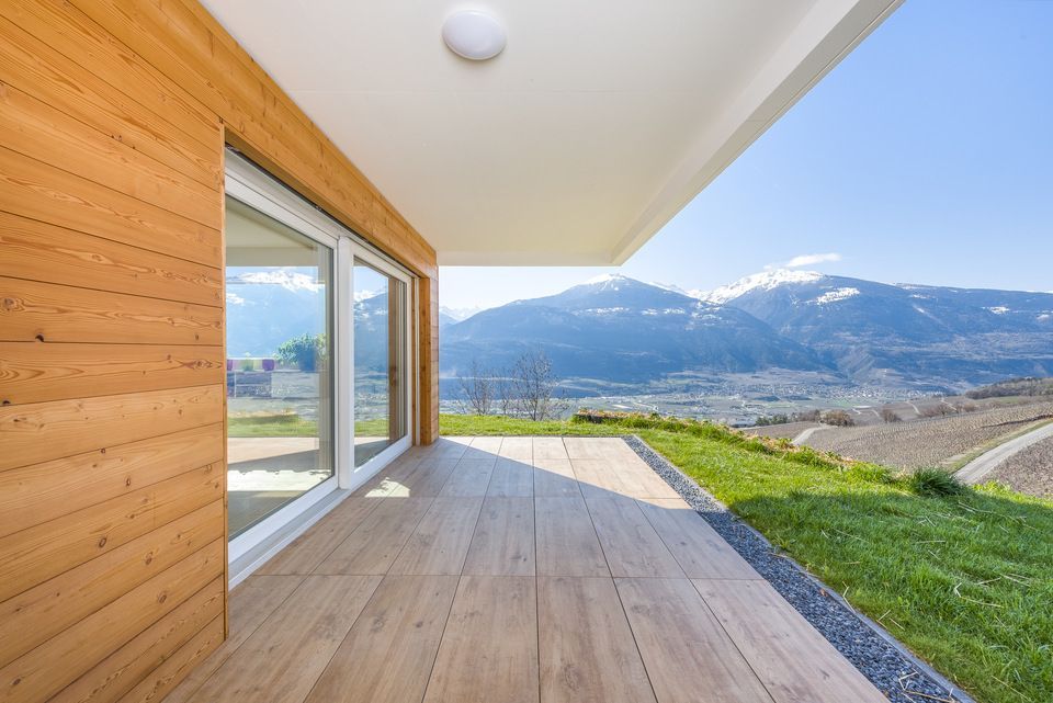 Une terrasse en bois avec vue sur les montagnes en arrière-plan.