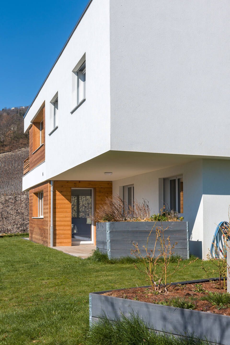 Une maison blanche et en bois avec une pelouse devant