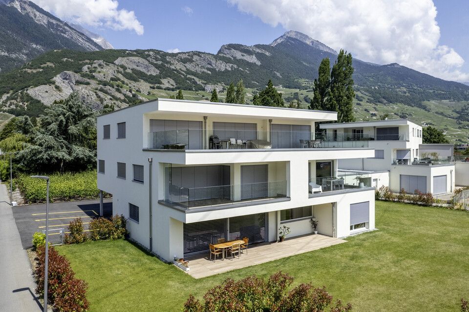 Une vue aérienne d'un immeuble d'appartements moderne avec des montagnes en arrière-plan.