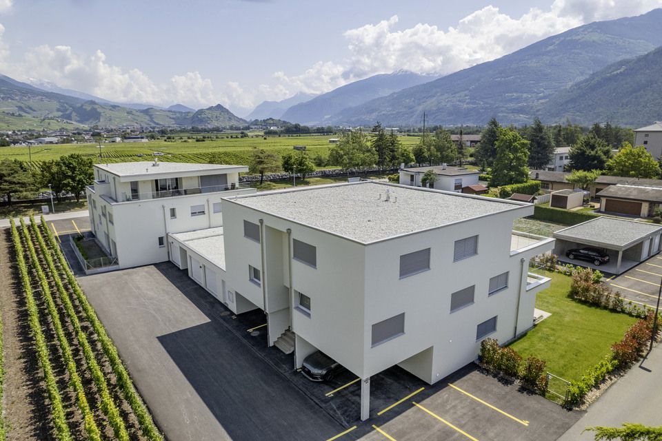 Une vue aérienne d'un grand bâtiment blanc avec des montagnes en arrière-plan.