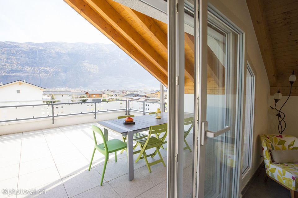 Un balcon avec une table et des chaises et une vue sur les montagnes