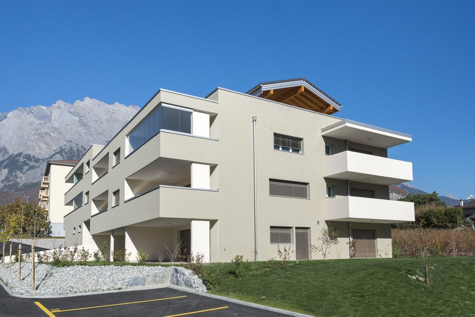 Un grand bâtiment blanc avec des balcons et des montagnes en arrière-plan