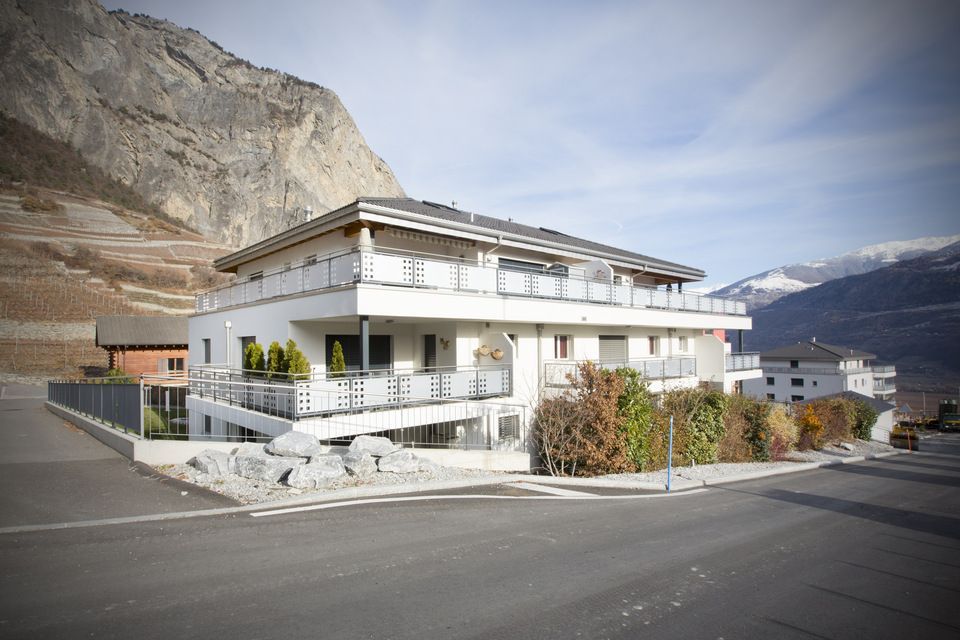 Un grand bâtiment blanc avec des balcons et des montagnes en arrière-plan
