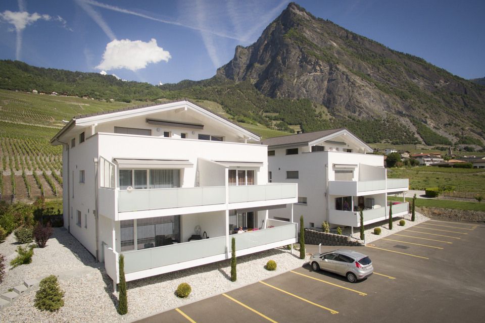 Une voiture est garée devant un bâtiment avec une montagne en arrière-plan.