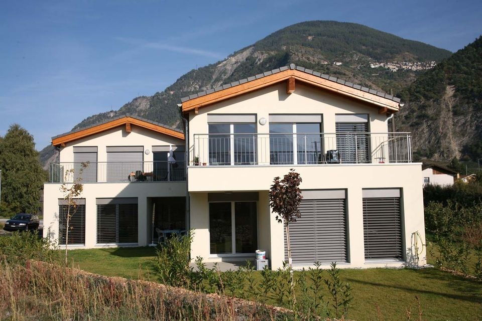 Une grande maison blanche avec des montagnes en arrière-plan