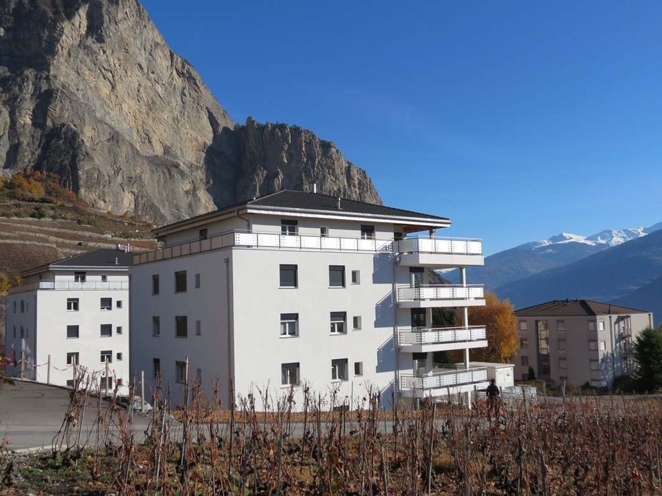 Un grand bâtiment blanc avec une montagne en arrière-plan