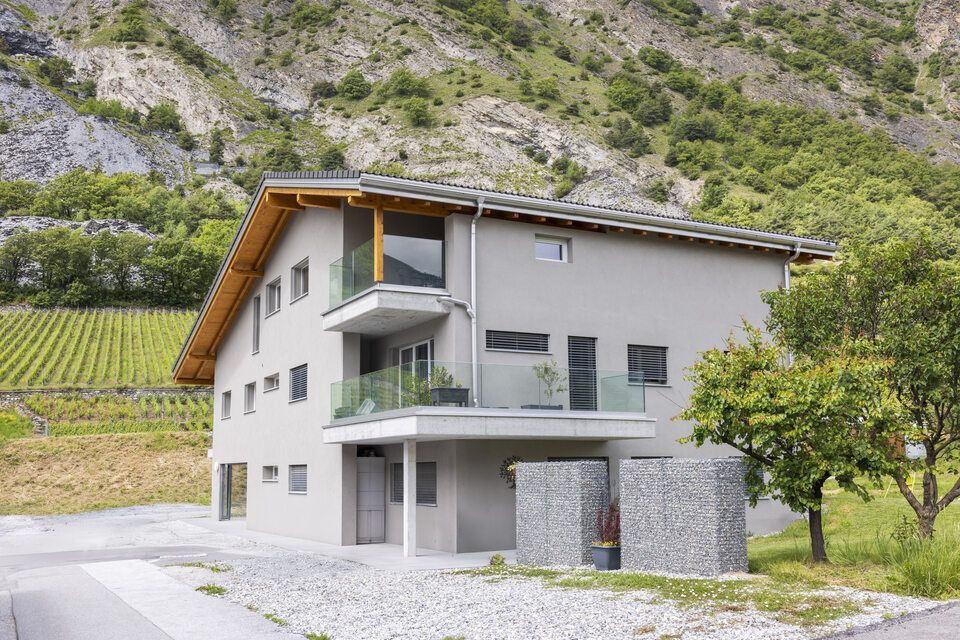 Une grande maison avec un balcon au milieu d'une montagne.