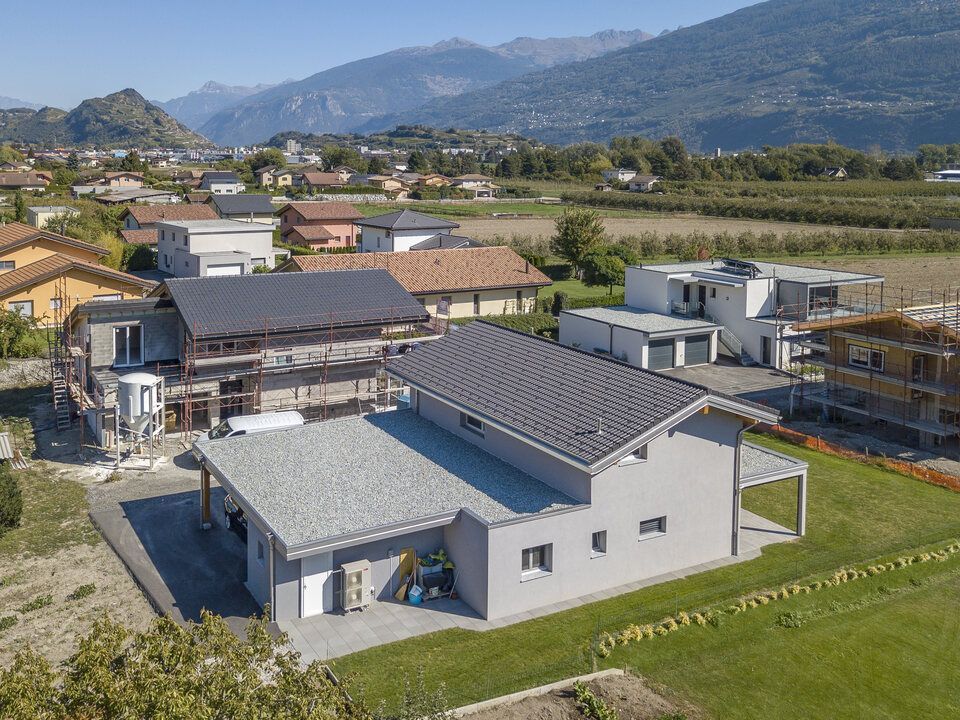 Une vue aérienne d'une maison en construction dans un quartier résidentiel avec des montagnes en arrière-plan.