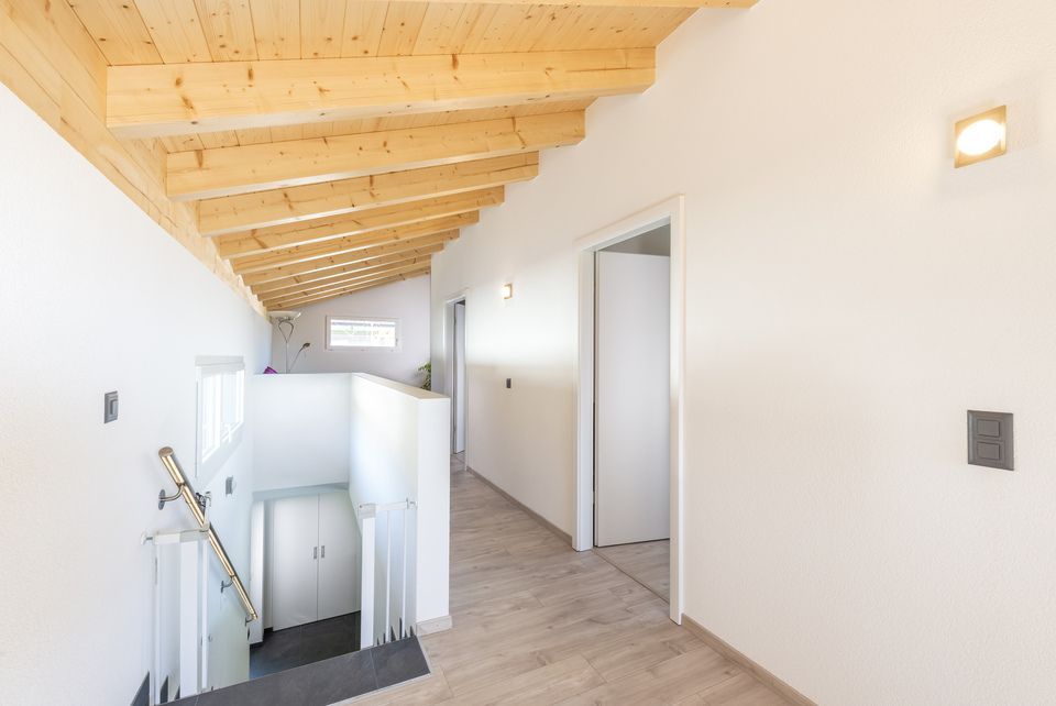 Un couloir avec un plafond en bois et des escaliers menant au deuxième étage.