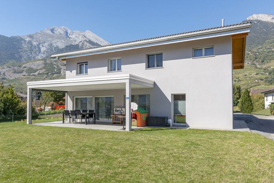 Une maison avec une pergola et des montagnes en arrière-plan