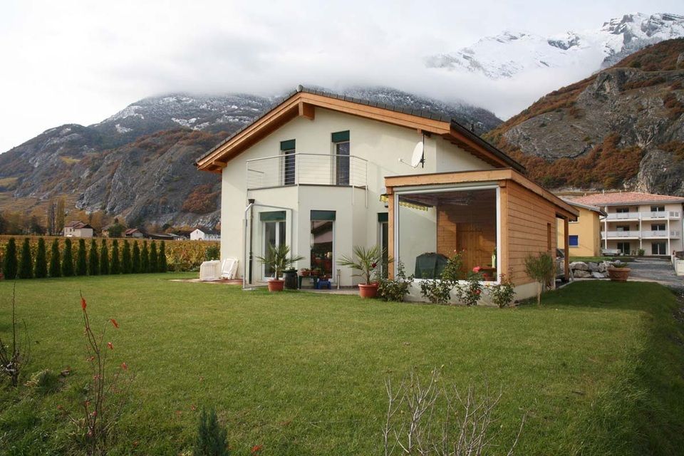Une maison avec une grande pelouse devant et des montagnes en arrière-plan
