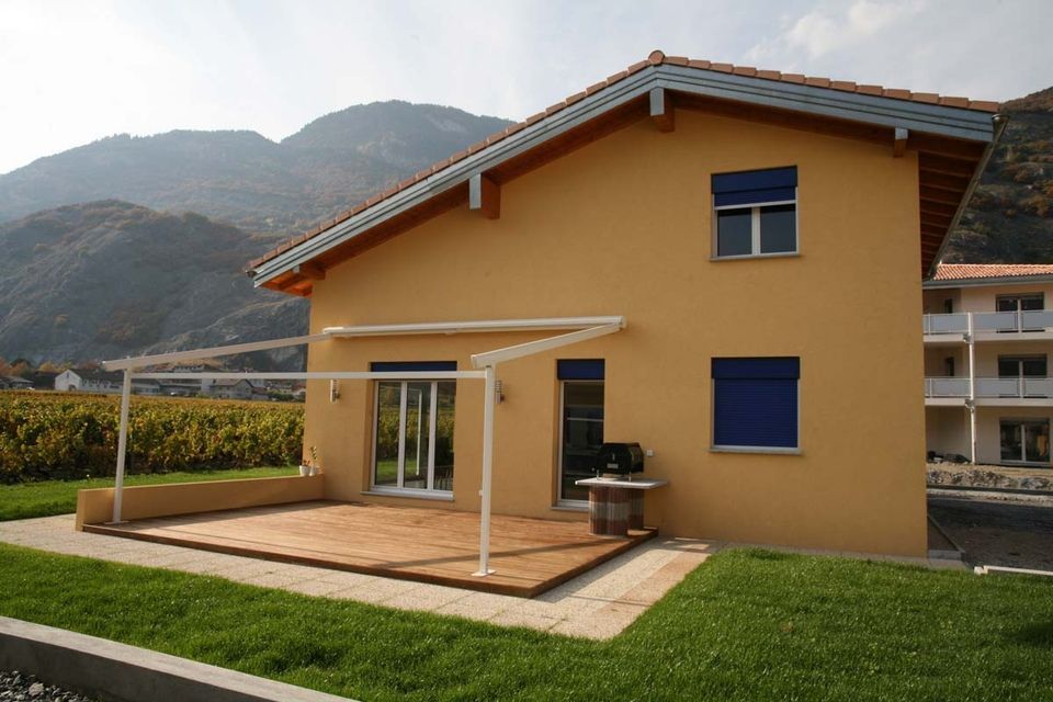 Une maison avec un patio et des montagnes en arrière-plan