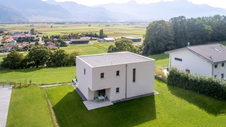 Une vue aérienne d'une maison blanche au milieu d'un champ herbeux.