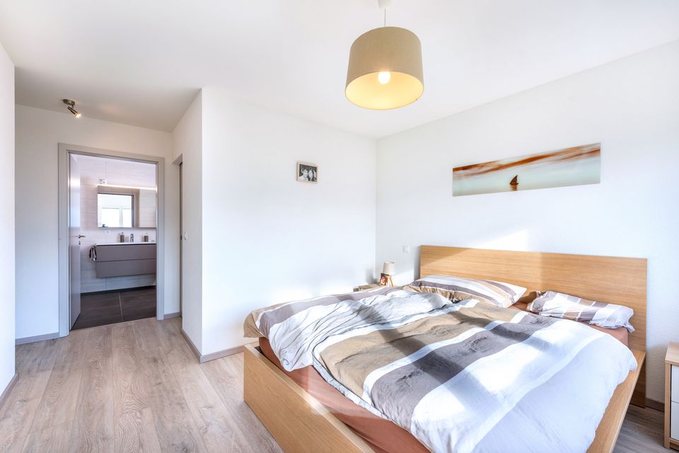 Une chambre avec un grand lit et une salle de bain en arrière plan.