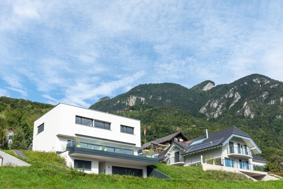 Quelques maisons situées au sommet d'une colline avec des montagnes en arrière-plan.