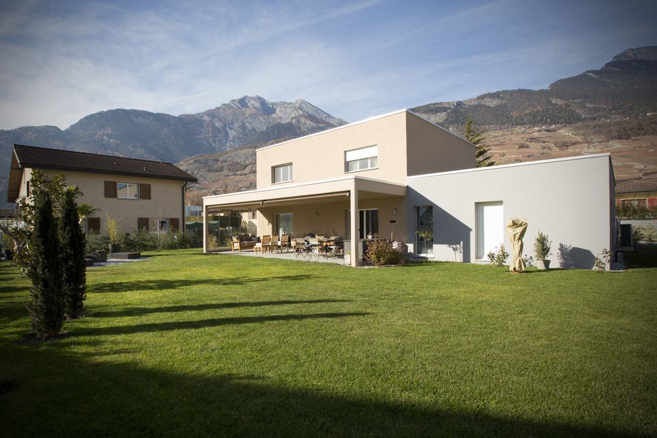 Une maison avec une grande pelouse devant et des montagnes en arrière-plan