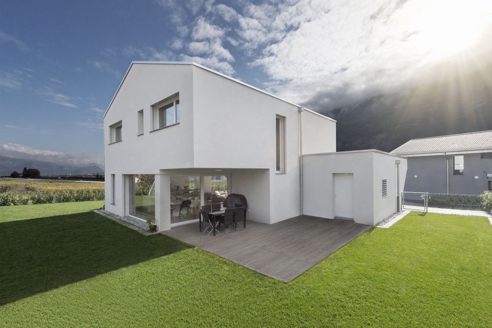 Une maison blanche avec une grande pelouse devant.