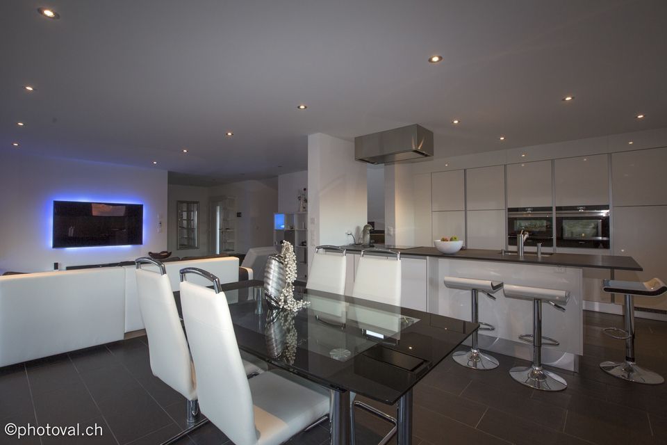 Une salle à manger avec une table en verre et des chaises blanches