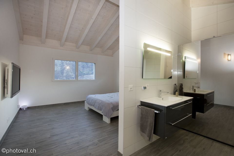 Une chambre avec un lit, un lavabo, un miroir et une télévision.