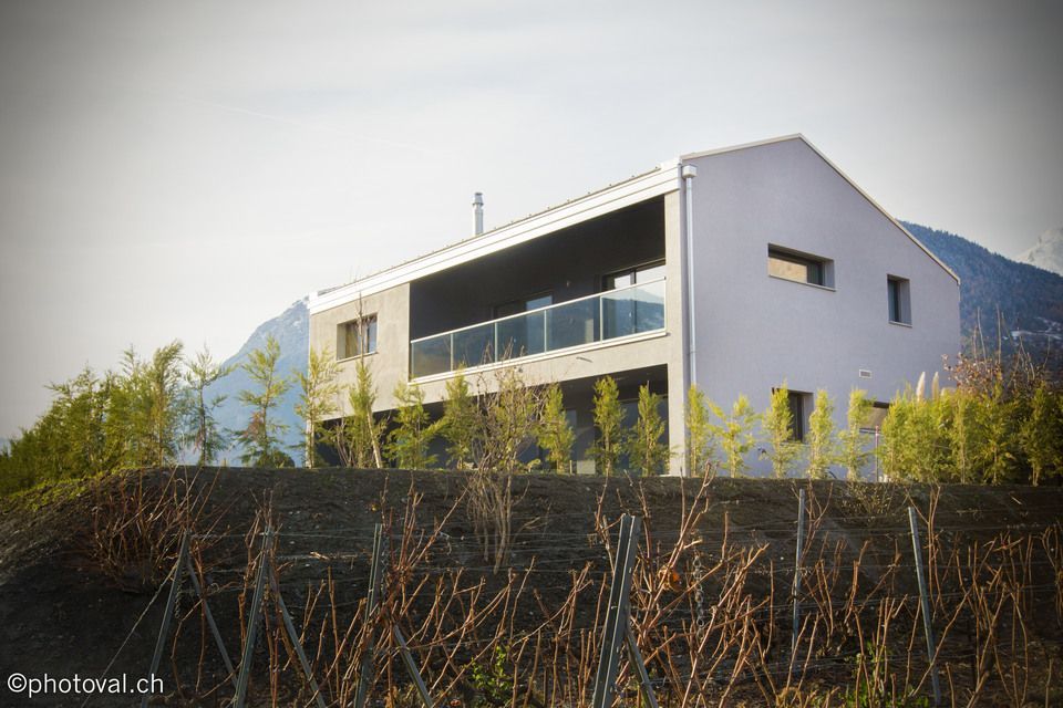 Une grande maison blanche est assise au sommet d'une colline entourée d'arbres.
