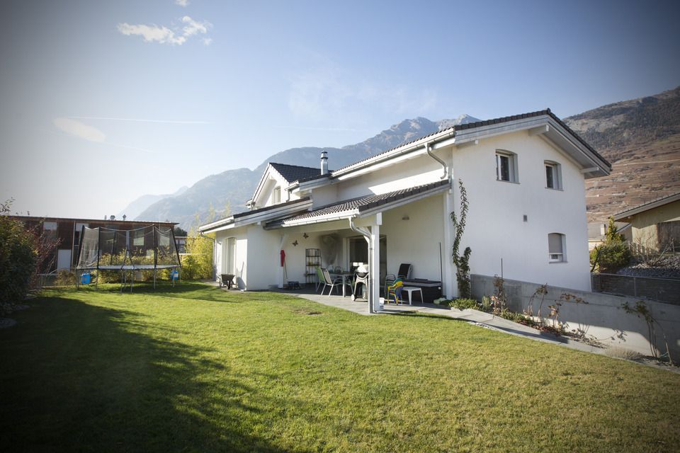 Une maison blanche avec une grande pelouse devant elle