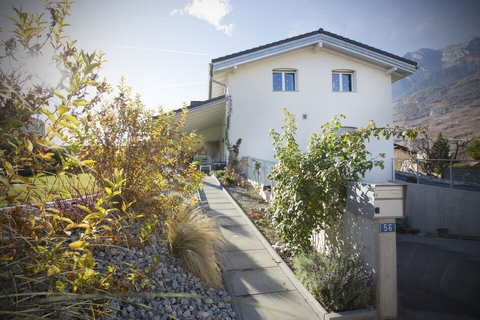 Une maison blanche avec une boîte aux lettres devant.
