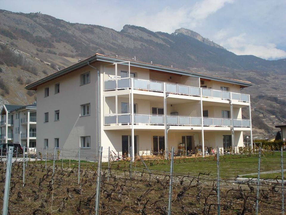 Un grand bâtiment blanc avec des balcons et des montagnes en arrière-plan